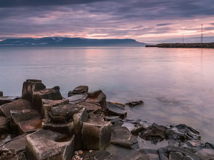 Basalt columns on the shore at Hofsós looking across Skagafjörður under a pink evening sky